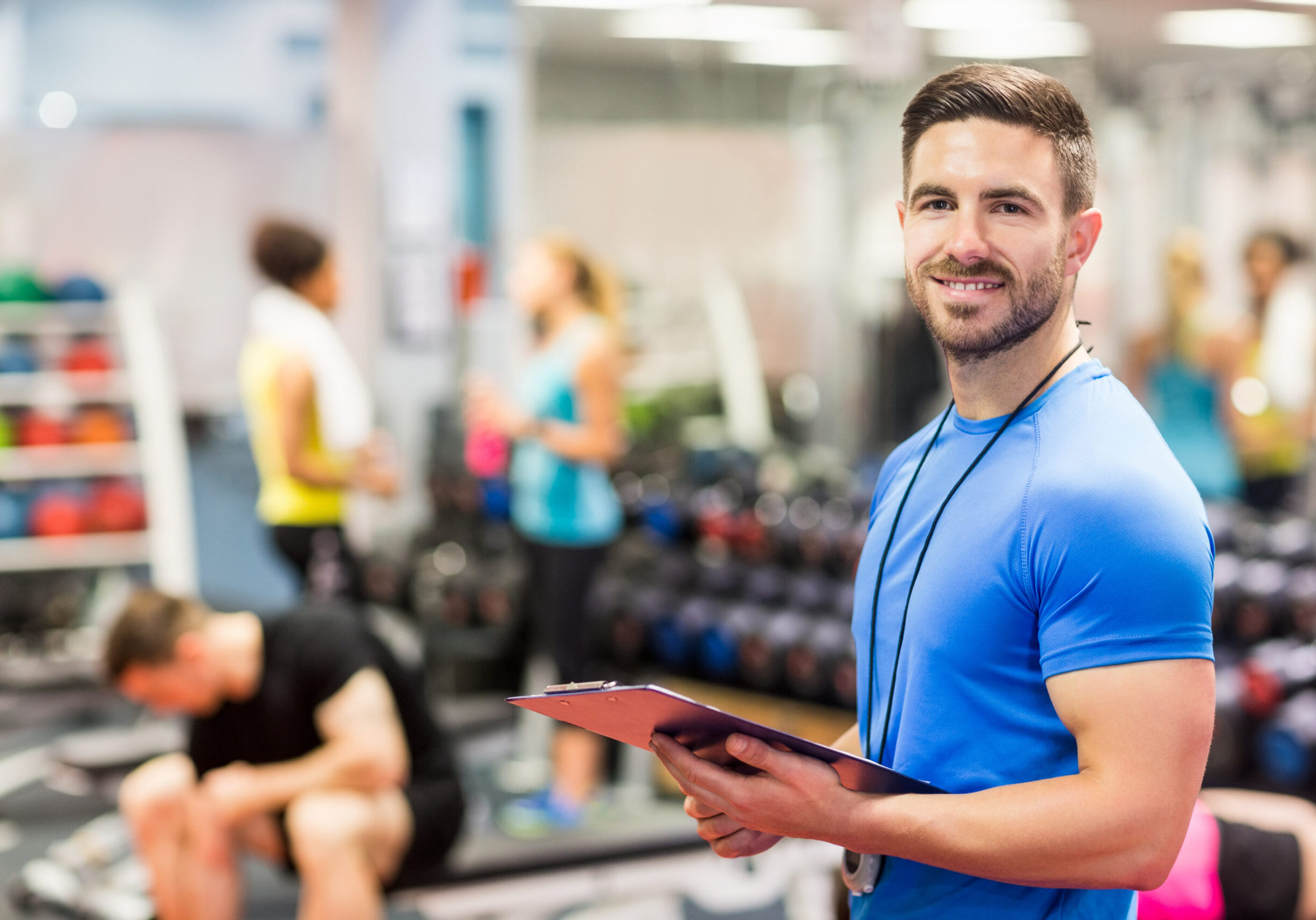 Handsome trainer smiling at camera at the gym