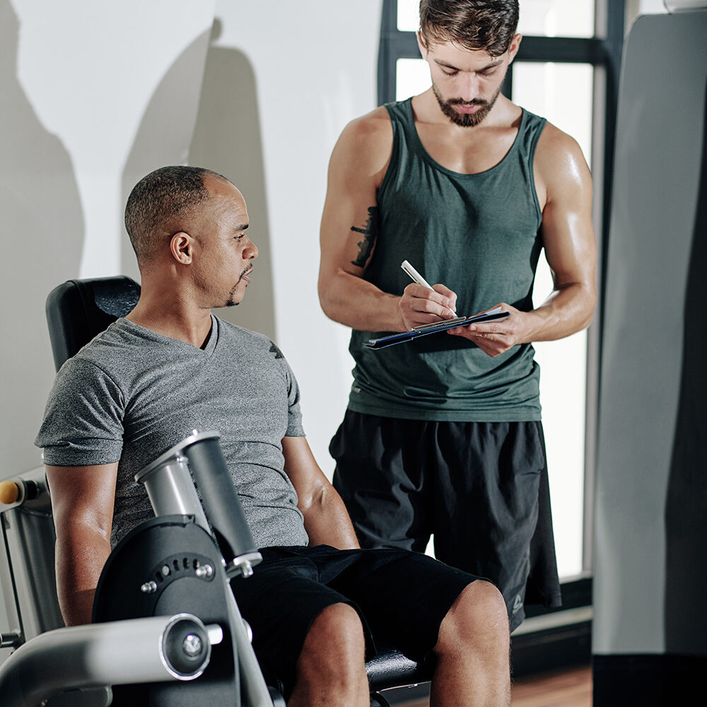mature-fit-man-doing-exercise-leg-extension-machine-when-his-trainer-taking-notes-resize mature-fit-man-doing-exercise-leg-extension-machine-when-his-trainer-taking-notes-resize